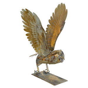 Metal owl sculpture with open wings on a white background
