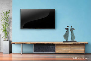 Modern living room with a flat-screen TV mounted on a light blue wall, wooden console table, and decorative items.